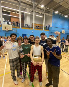 a picture of the mens basketball team posing with a homemade trophy