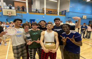 a picture of the mens basketball team posing with a homemade trophy