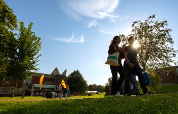 Students walking on campus with trees and buildings in the background