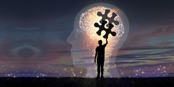 An illustration of a silhouetted man reaching for jigsaw pieces inside the outline of head