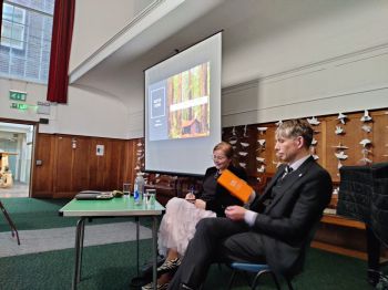 Two people seated in front of a screen.