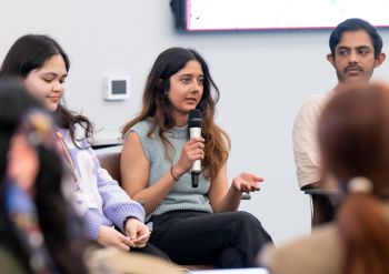 Davina Vallabh, a young professional, holding a microphone and addressing an audience