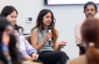 Davina Vallabh, a young professional, holding a microphone and addressing an audience
