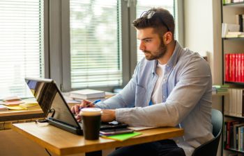 Image showing a man sat at a desk and working on a laptop.