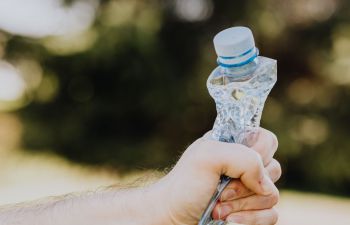 Man's hand squeezing a used plastic bottle