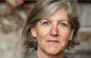 Professor Ann Light in front of a grey background looking at the camera