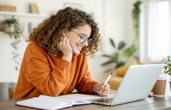 Woman with curly hair smiling at laptop