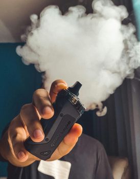 A close up of someone vaping with a cloud of smoke above their fingers