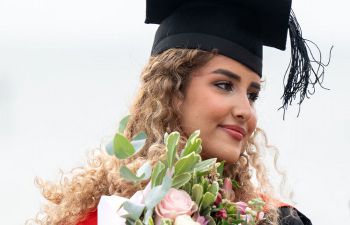 Student in a Graduation gown holding flowers