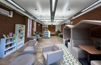 Wellbeing area with comfortable seating, study booths, and shelves containing wellbeing books