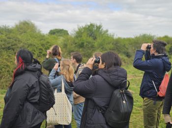 A group of students using binoculars to spot Stork chicks in their nests.