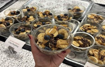 A hand holding a breakfast bowl of yoghurt with fruit toppings.