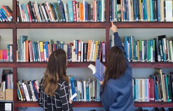 Two students browse books in the library