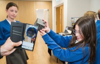 Two students using the merge cube in a presentation at school