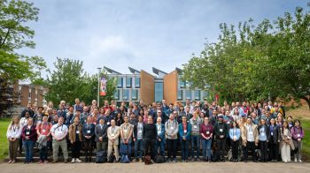 Attendees of WIN25 conference standing outside in a large group in front of a building