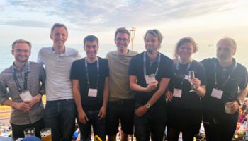 WIN25 conference organisers standing together in a group by the seafront smiling and holding drinks.