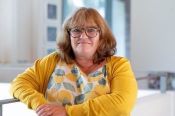 A portrait photo of a smiling Jo Tregenza taken from inside Essex House.