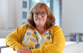 A portrait photo of a smiling Jo Tregenza taken from inside Essex House.