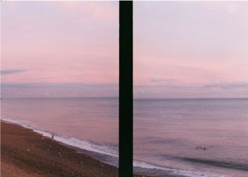 An image of the seafront split by a object in the foreground creating an abstract dark strip.