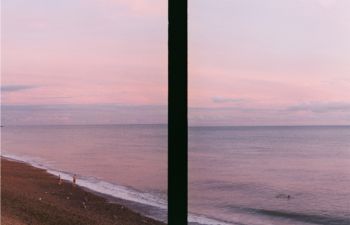An image of the seafront split by a object in the foreground creating an abstract dark strip.