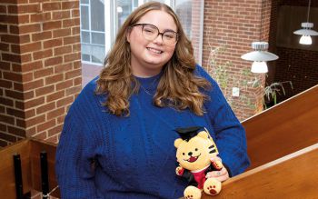 A girl smiling at the camera and holding a teddy bear
