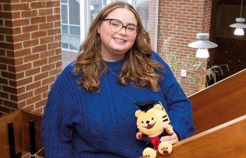 A girl smiling at the camera and holding a teddy bear
