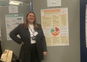 A smiling student next to her winning poster