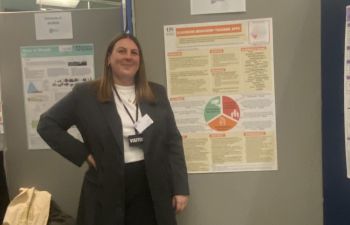 A smiling student next to her winning poster
