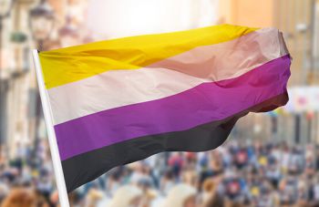 A non-binary flag flies from a flag pole