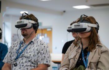 Three people sitting with virtual reality headsets on