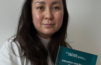 Head shot of woman with long dark hair holding her dissertation