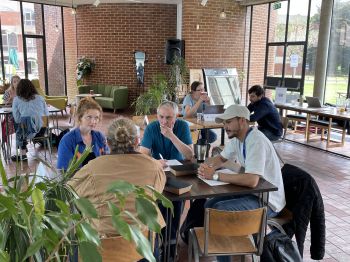 Researchers gathered around a table, having a discussion over food and drinks