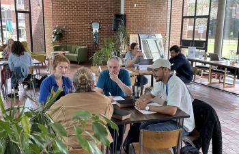 Researchers gathered around a table, having a discussion over food and drinks