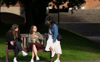 Students sitting on a bench chatting and smiling