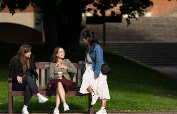 Students sitting on a bench chatting and smiling