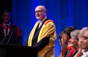 Marcus David Hayes standing at a podium giving a speech at the graduation ceremony