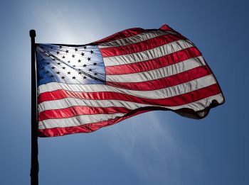 An American flag backlit against a blue sky
