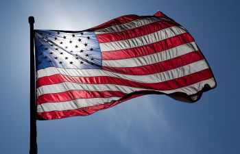 An American flag backlit against a blue sky