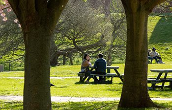 Two individuals sat at a campus picnic table