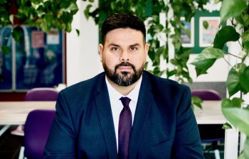 Image of Abdlrhman wearing a suit and sitting surrounded by plants
