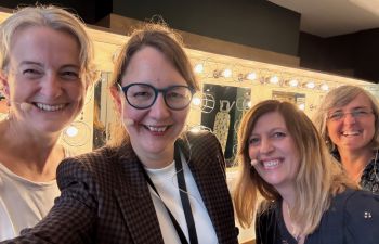 The 4 panellists are shown close up and smiling in a 