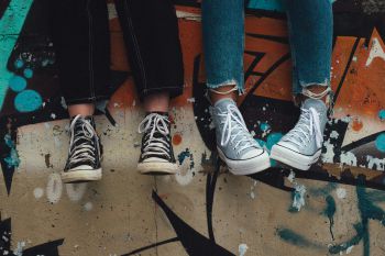 Colour photograph of two individuals sitting on a spray painted wall