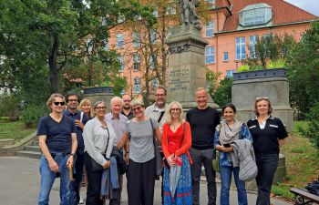 A photograph of all presenters standing in a group outside Charles University in Prague smiling for the camera