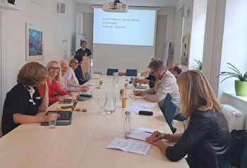 10 academics are shown smiling and working together around a table in a conference break-out session.
