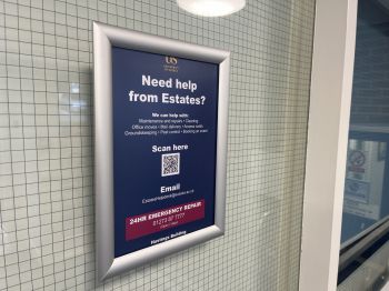 A photo of a QR code reporting poster in an academic building