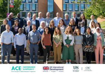 Male and female researchers standing together looking at the camera in front of the Sussex Business School