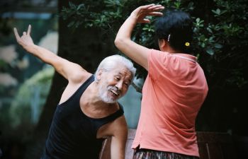 An image of two Chinese people smiling whilst practising Tai Chi