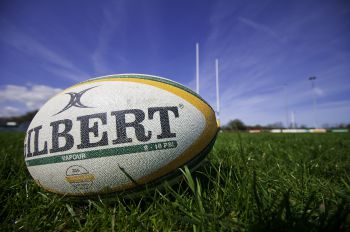 A rugby ball manufactured by Gilbert rugby, laying on a rugby pitch