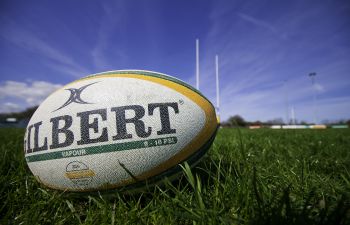 A rugby ball manufactured by Gilbert rugby, laying on a rugby pitch