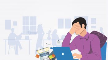 A man is at his laptop, visibly stressed with his hand over his eyes. There are other colleagues faded in the background